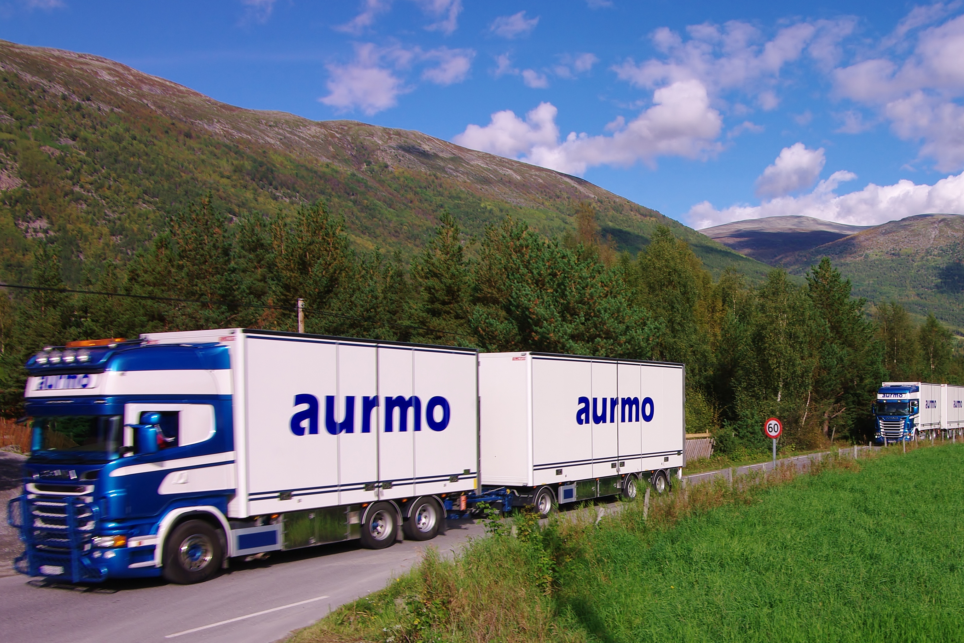 Bilde av transportfirmaet Aurmo Transport sine biler som kjører på en norsk vei.